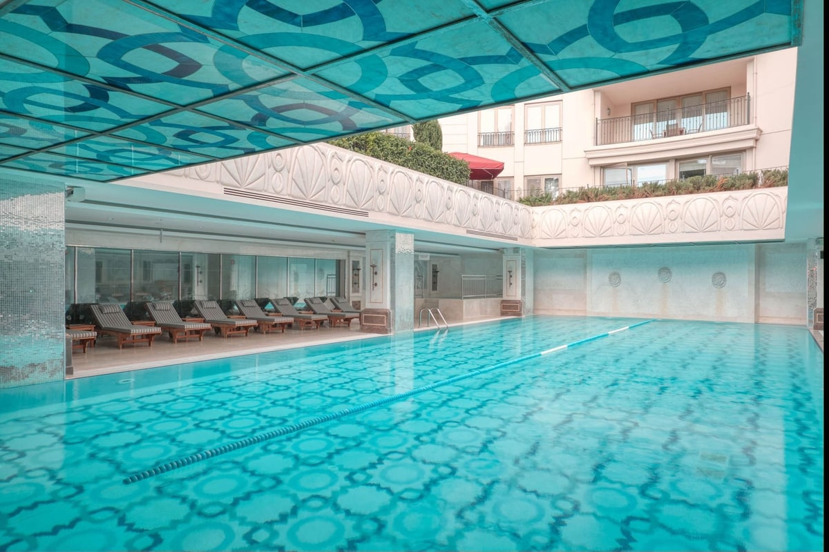 Indoor pool with blue-tile geometry under a glass ceiling