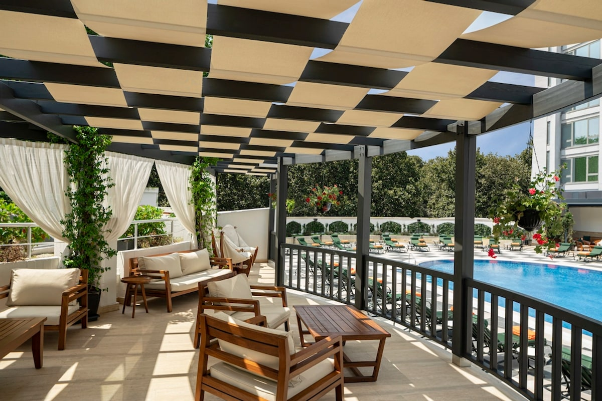Outdoor pool surrounded by garden and white gazebos