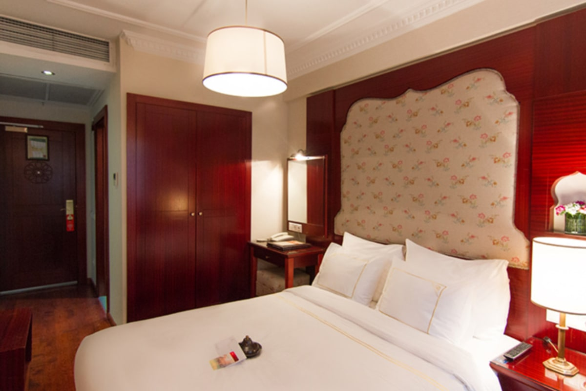 Deluxe room interior with carved-wood headboard.